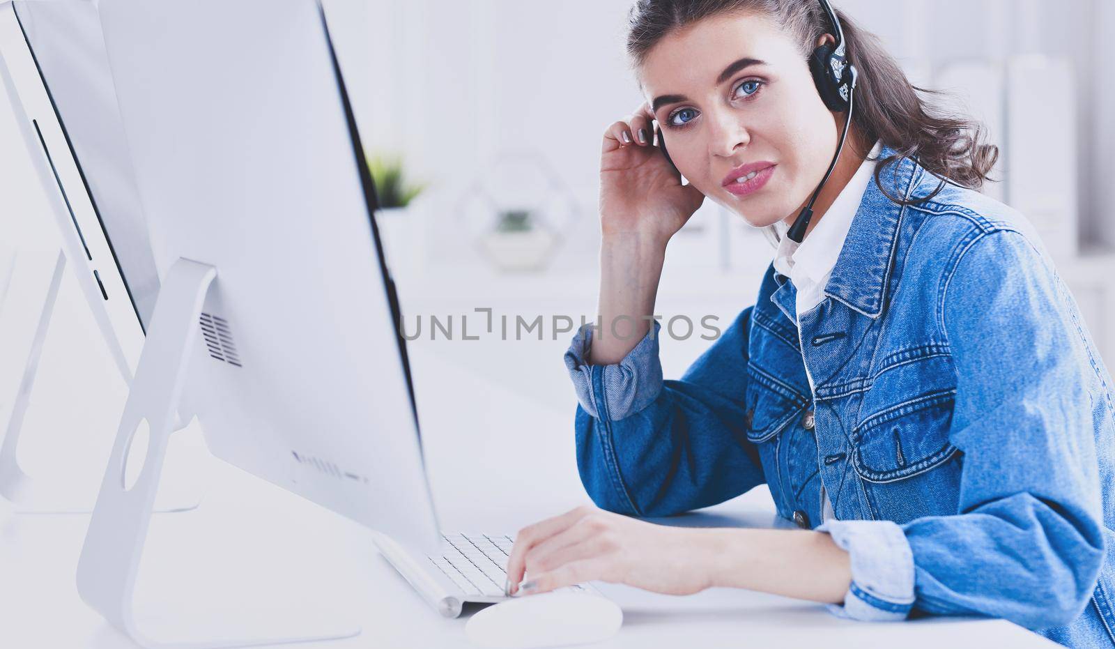 Portrait of beautiful business woman working at her desk with headset and laptop
