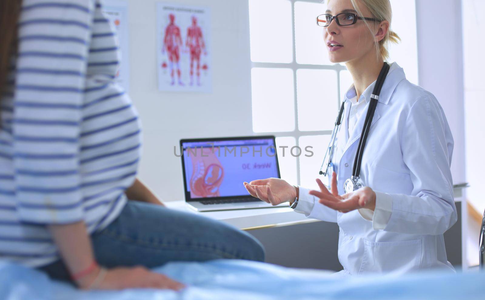 Beautiful smiling pregnant woman with the doctor at hospital.