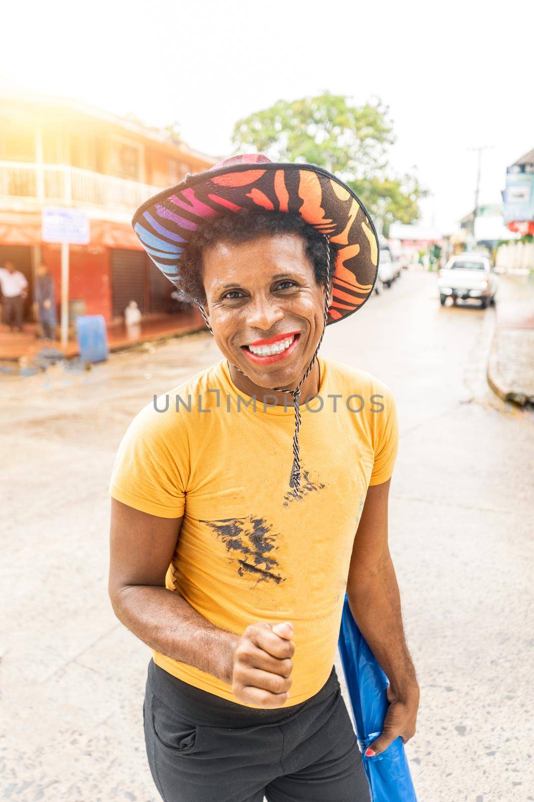 Vertical photo of a black skinned latin gay man with colorful hat smiling and looking at camera by cfalvarez