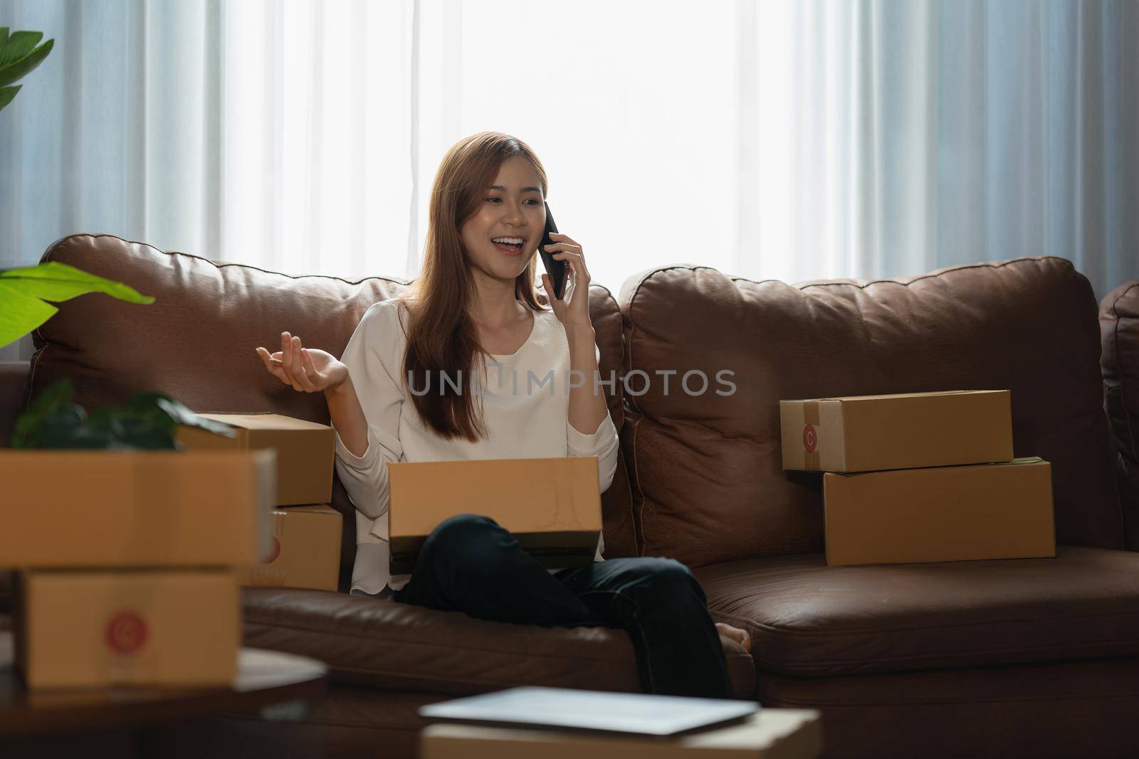Image of Young asian woman startup freelance with parcel box and talking with customer by phone. Online marketing packing box delivery concept. by itchaznong