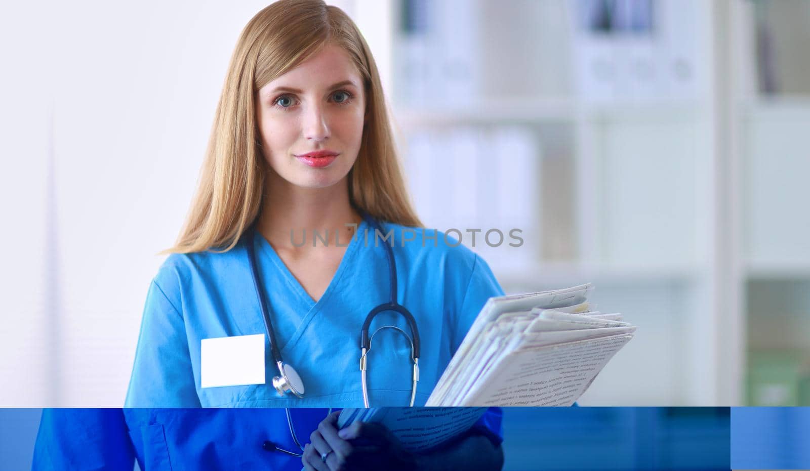 Portrait of woman doctor with stethoscope at hospital corridor, holding a folder