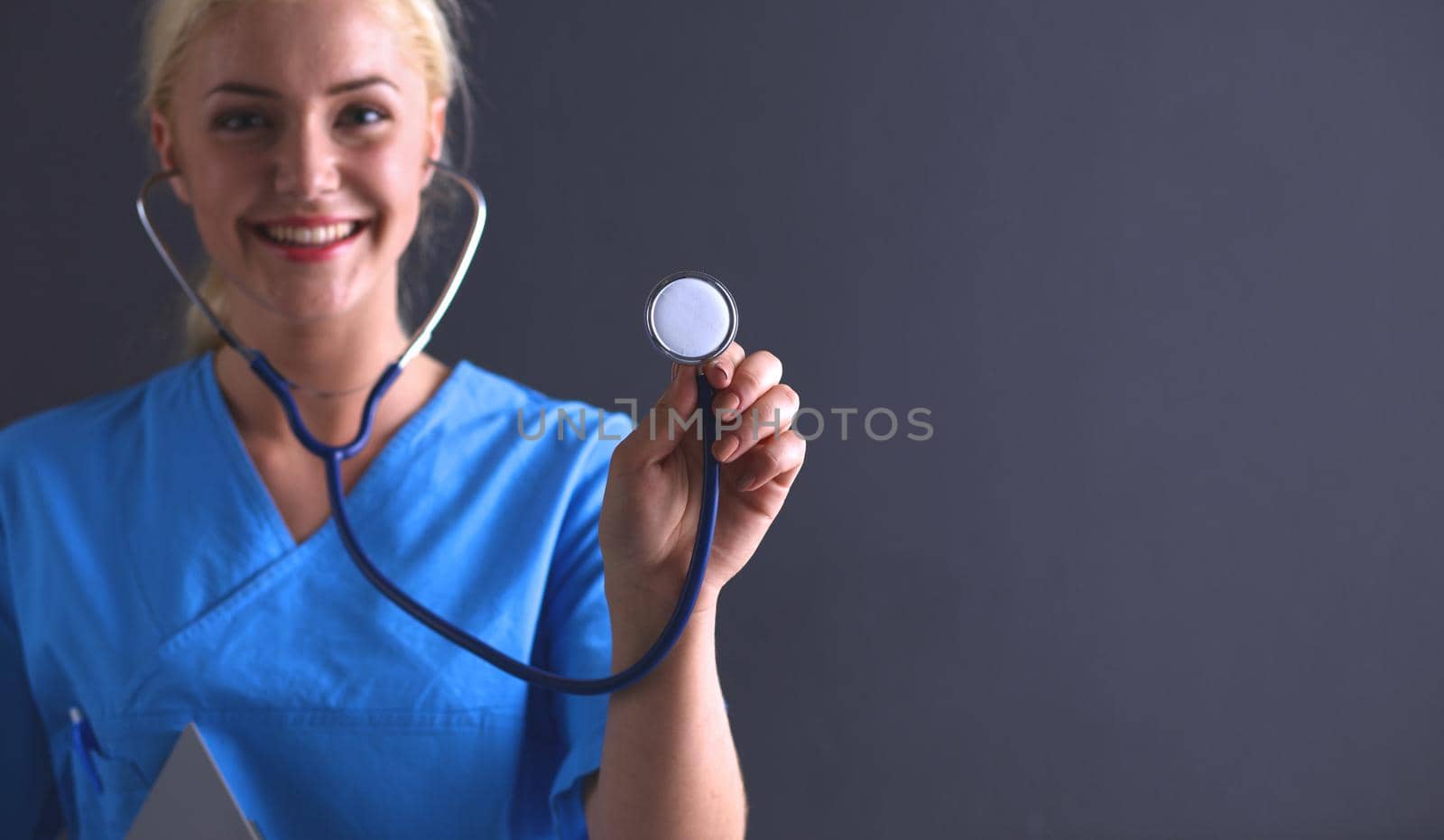 Female doctor with a stethoscope listening, isolated on gray background.