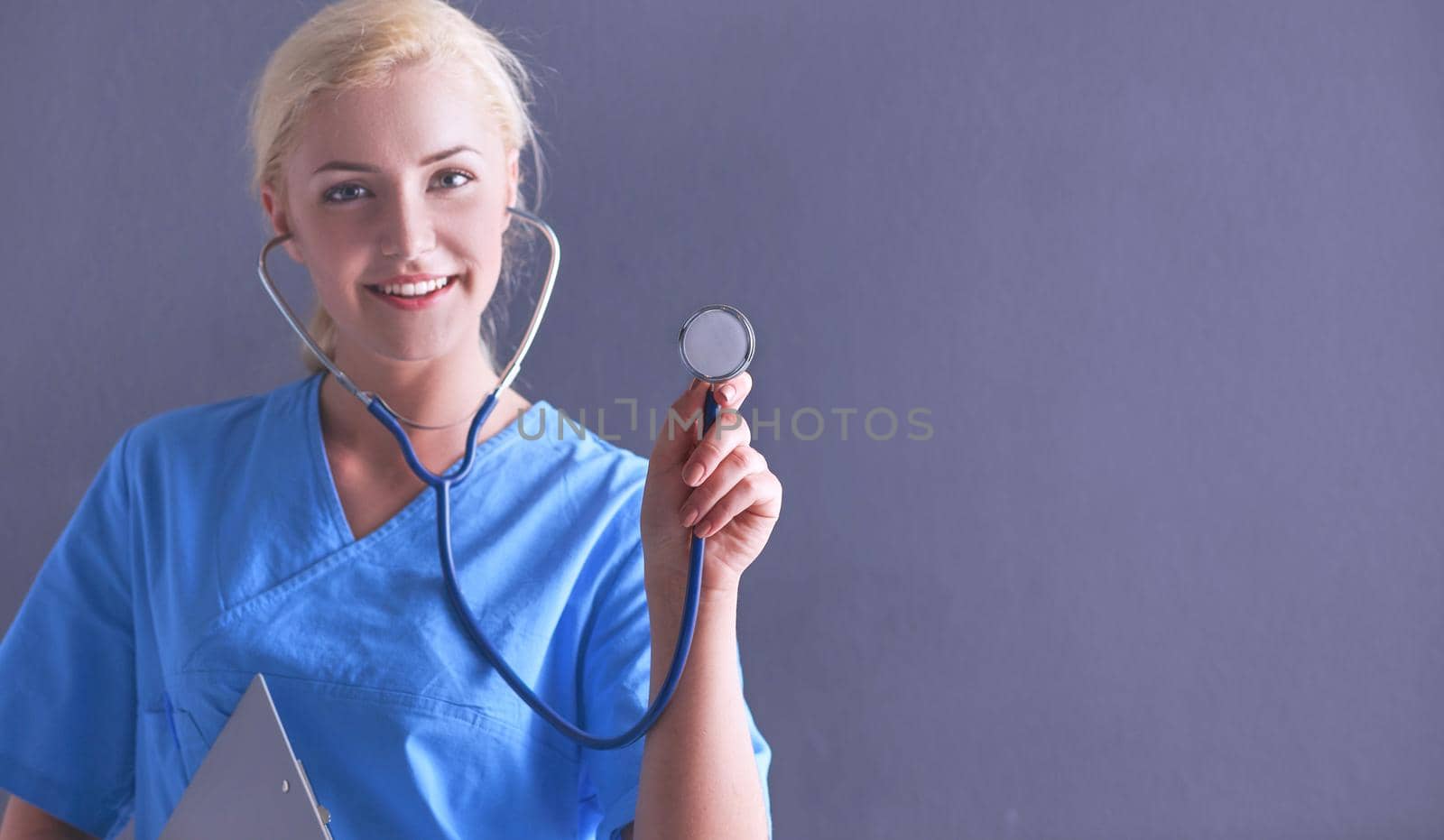 Female doctor with a stethoscope listening, isolated on gray background.
