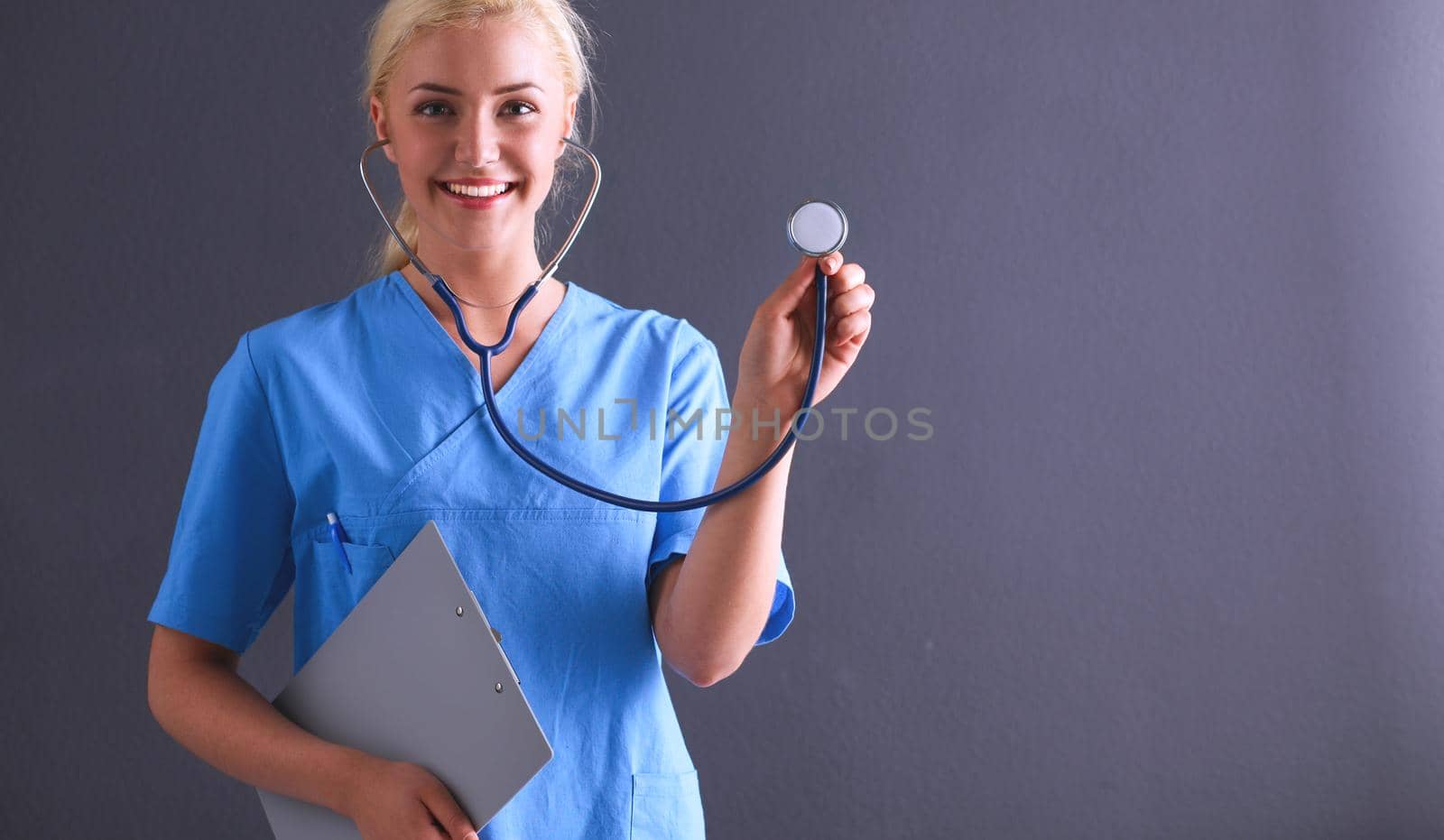 Female doctor with a stethoscope listening, isolated on gray background.