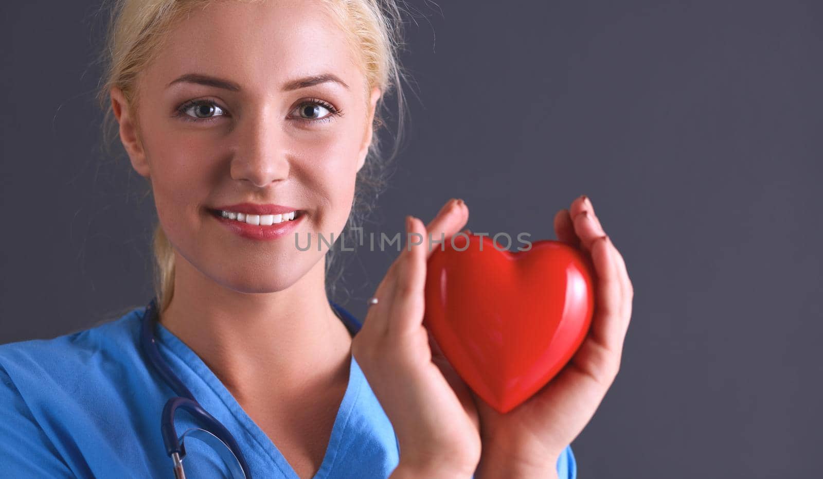 Young doctor woman with stethoscope holding heart .