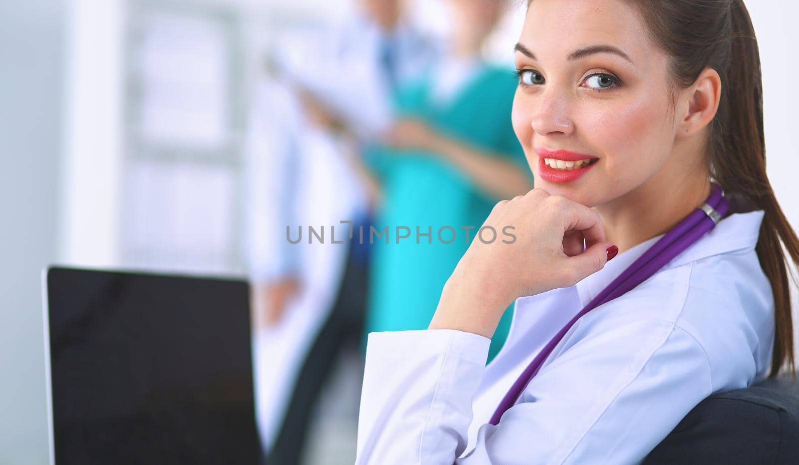 Beautiful young smiling female doctor sitting at the desk.