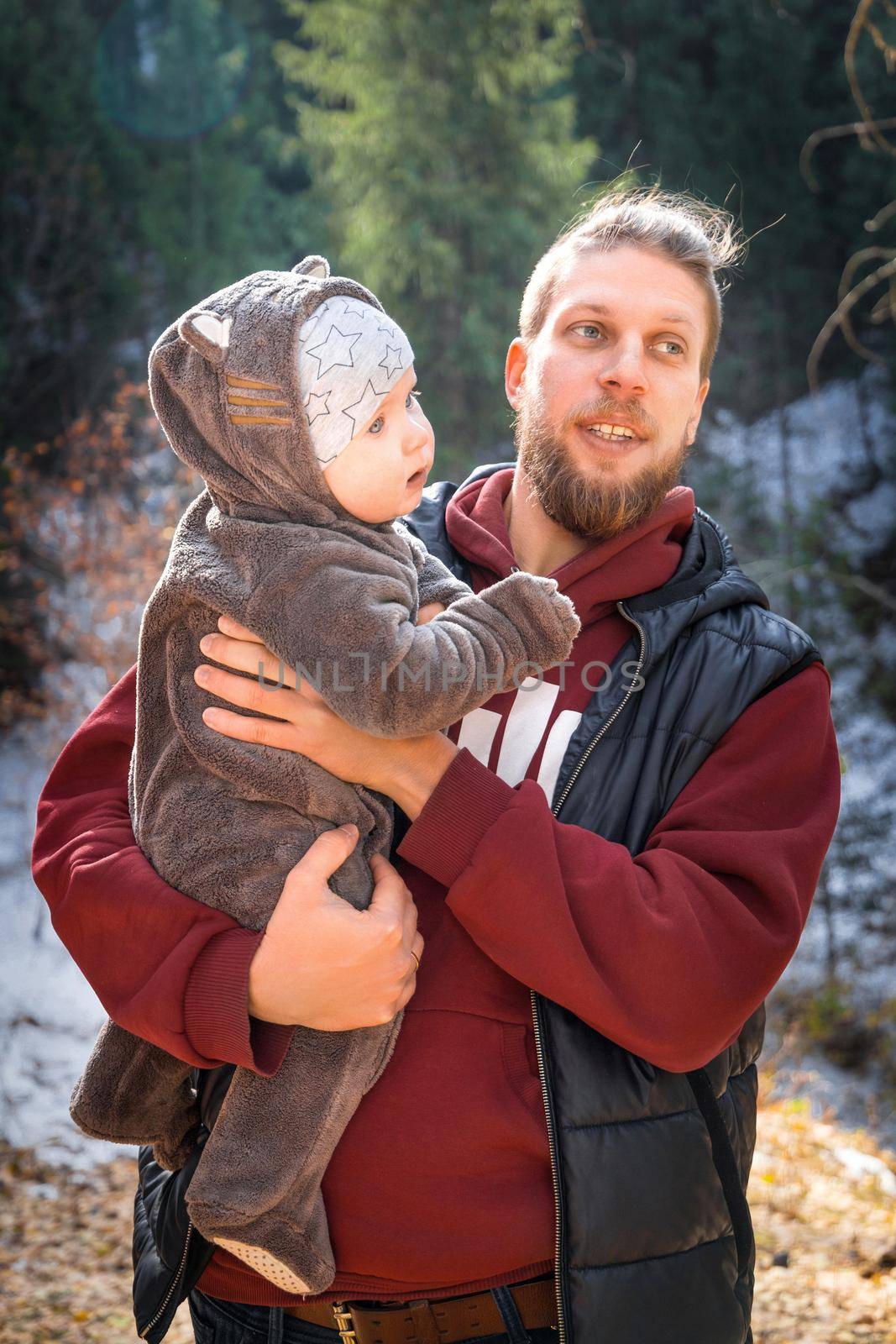Hipster bearded young father with his son in a funny jumpsuit with ears outdoor walk.