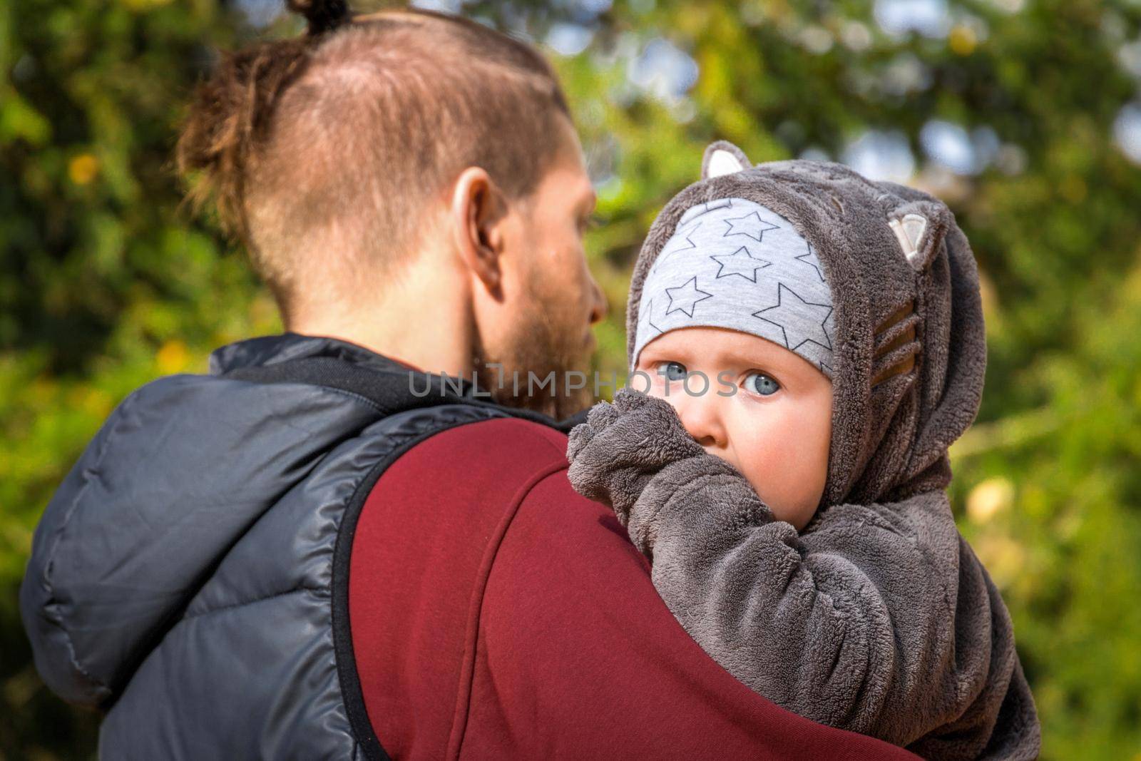 portrait of father and baby son against nature background, caucasian man holding his son.
