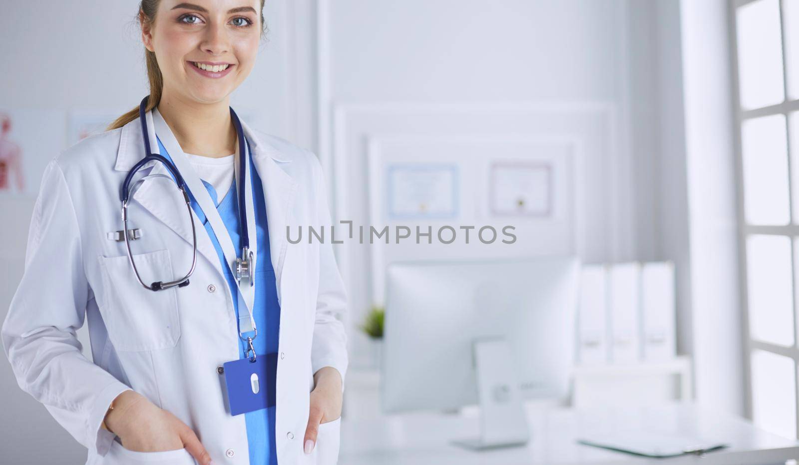 Portrait of young woman doctor with white coat standing in hospital.