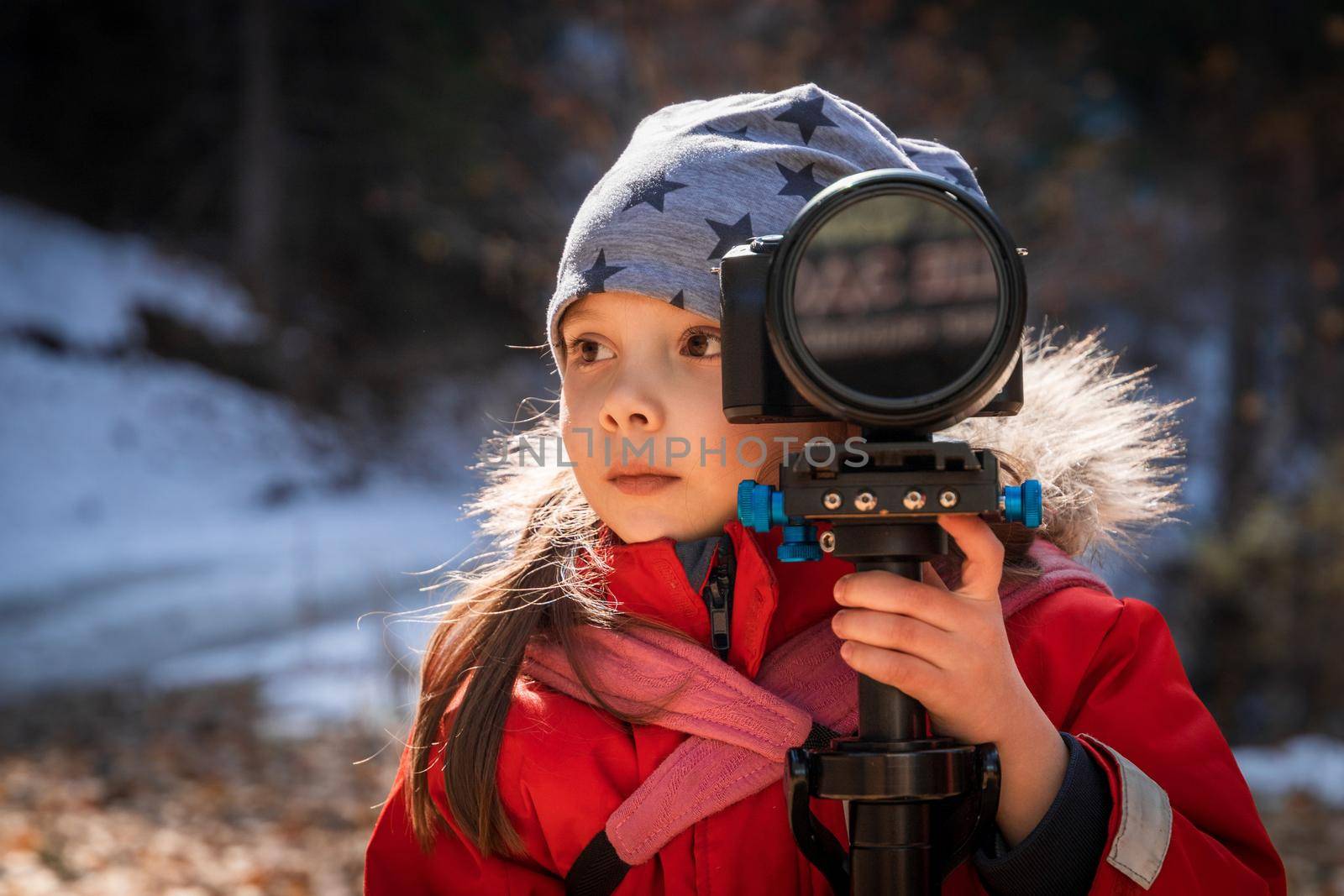 Little girl learning to take pictures with camera in nature.