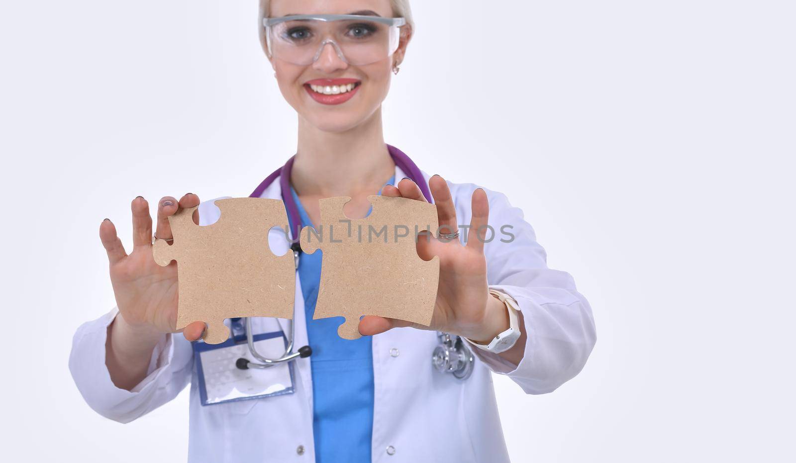 Woman doctor holding two connecting puzzle pieces.