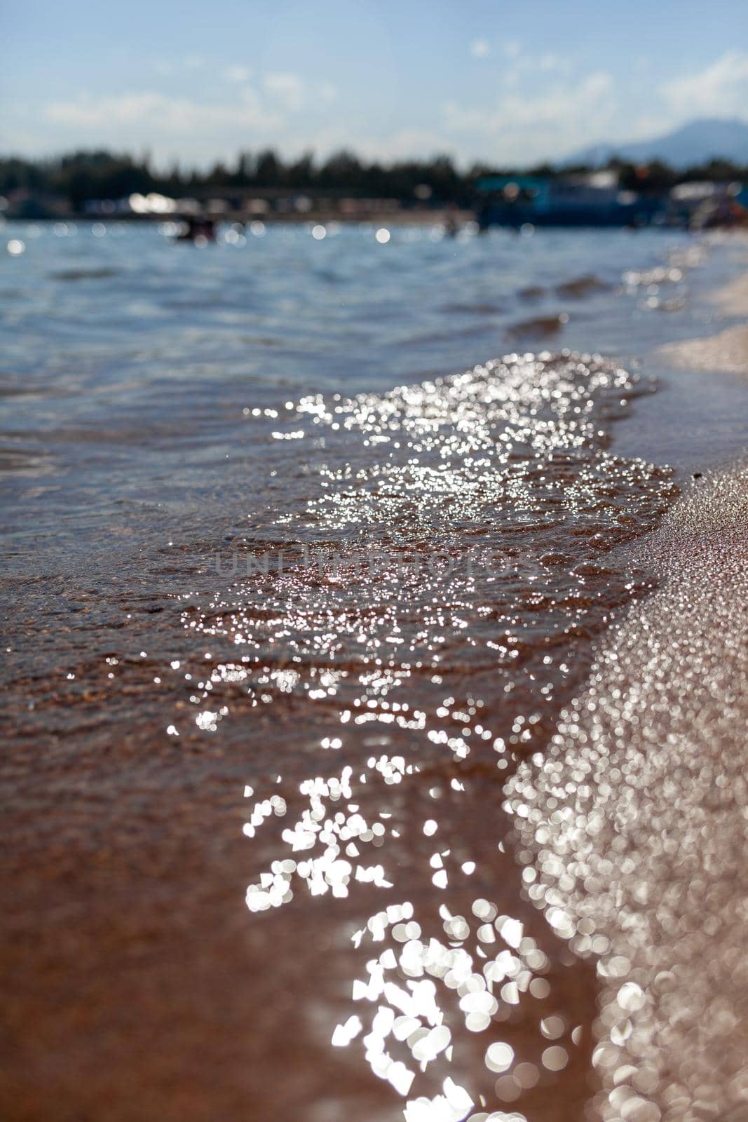 A soft wave runs on a sandy shore on a summer day. by AnatoliiFoto