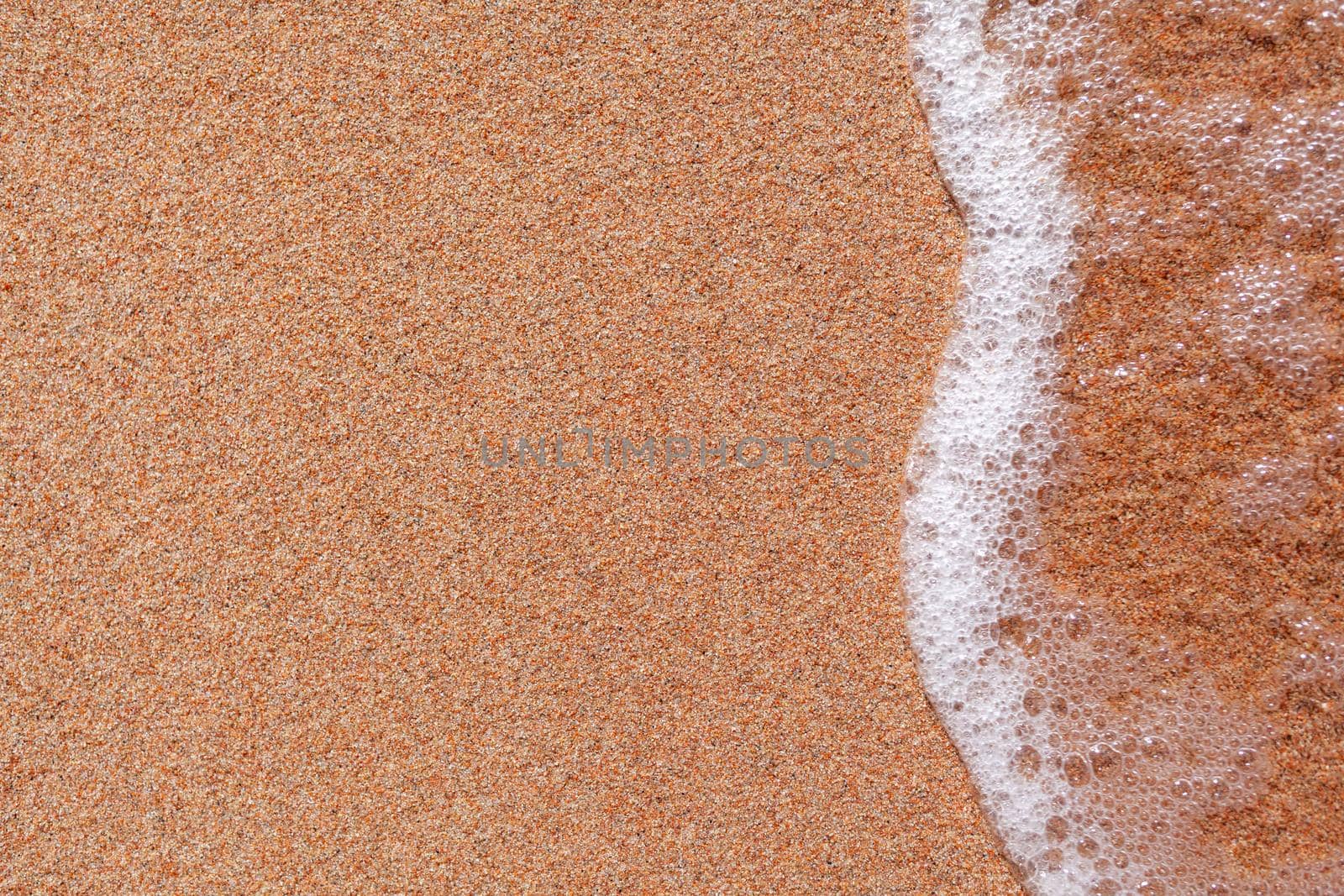 A soft wave runs on a sandy shore on a summer day. Empty space can be used as background for display or montage your top view products.