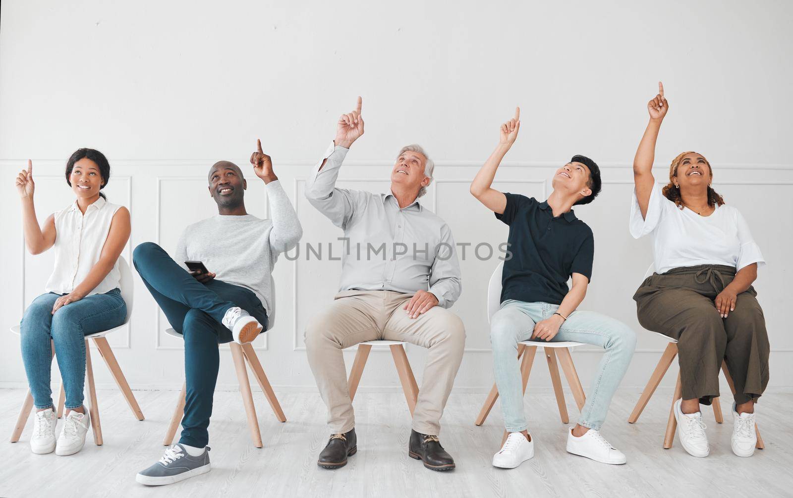 a diverse group of people pointing up while sitting in line against a white background.