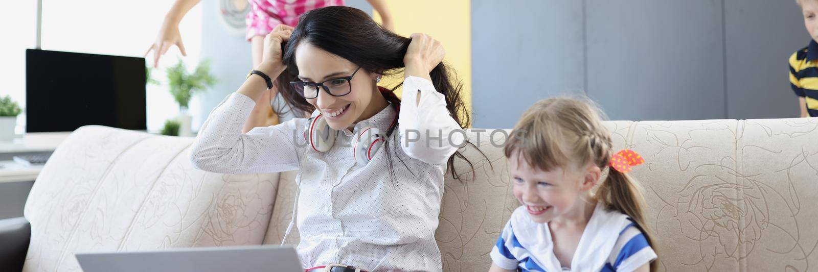 Portrait of happy woman working and playing with her kids on couch. Mother work from home, earn money for children. Parenthood, weekend, childhood concept