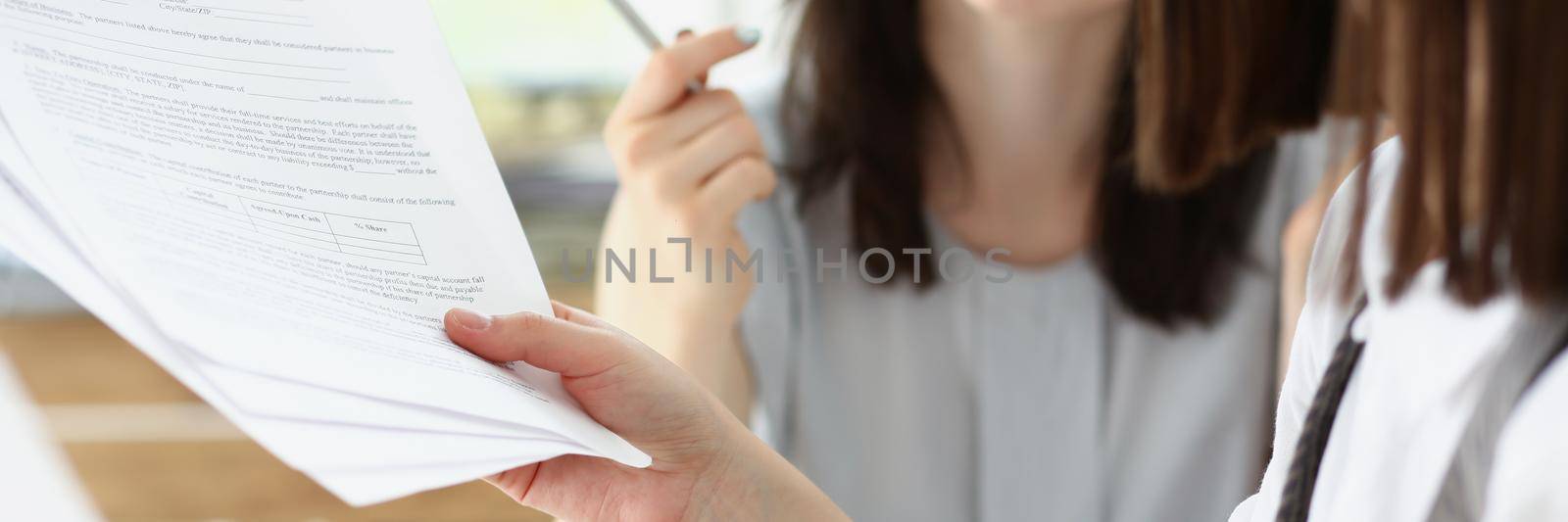 Close-up of business consultant showing business graphic report to colleague. Coworkers discuss working moments, share ideas in office. Business concept