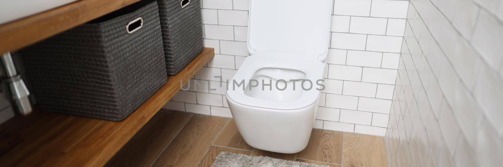 Portrait of modern bathroom interior with wooden shelves, white sink and toilet. Fresh interior, toilet paper, soap, decor. Renovation, restroom concept