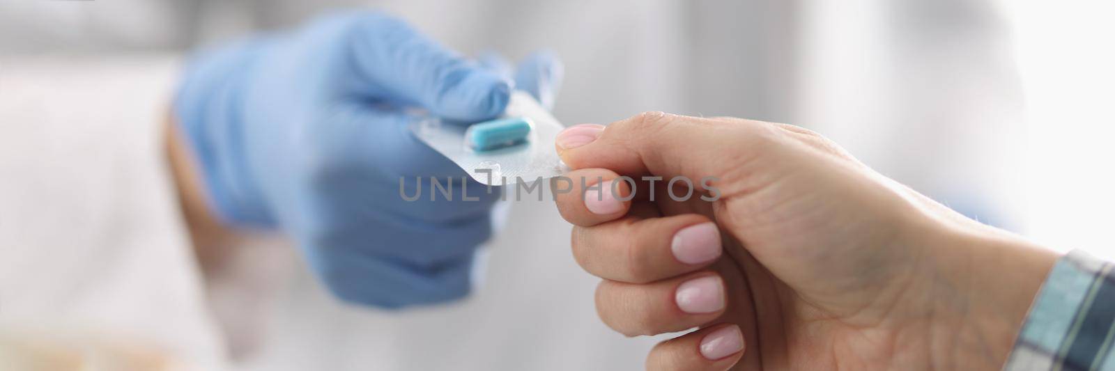 Female doctor in uniform give tablets in blister to patient by kuprevich