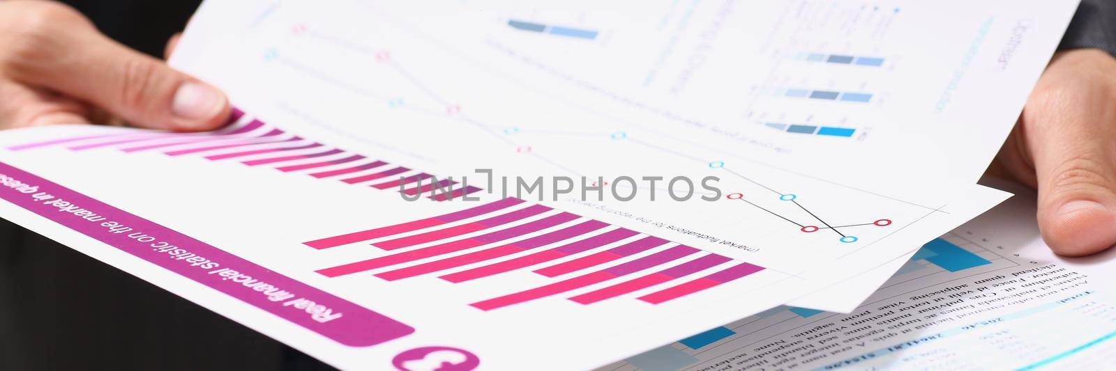 Businessman in suit holding agreement form or annual report in finance by kuprevich