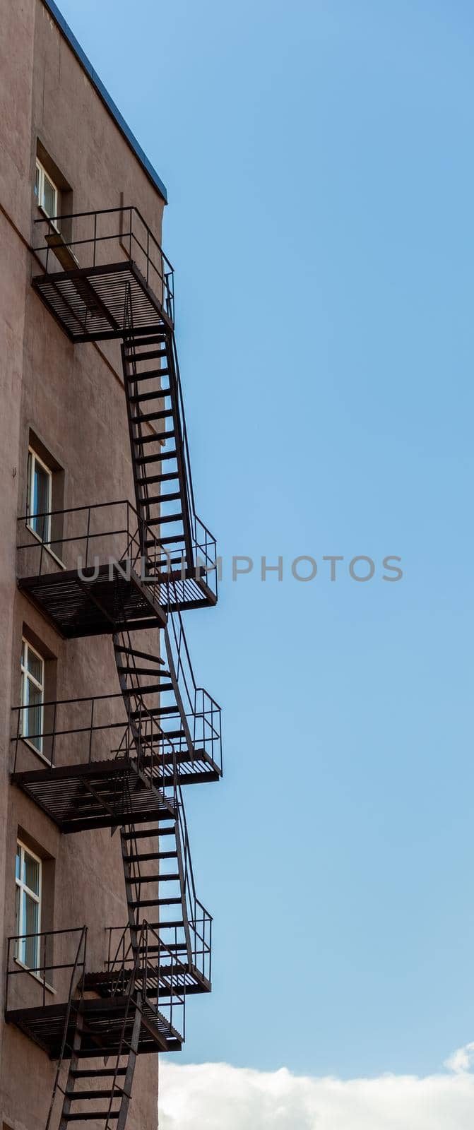 Silhouette of a fire escape on a high-rise building against a blue sky by AnatoliiFoto