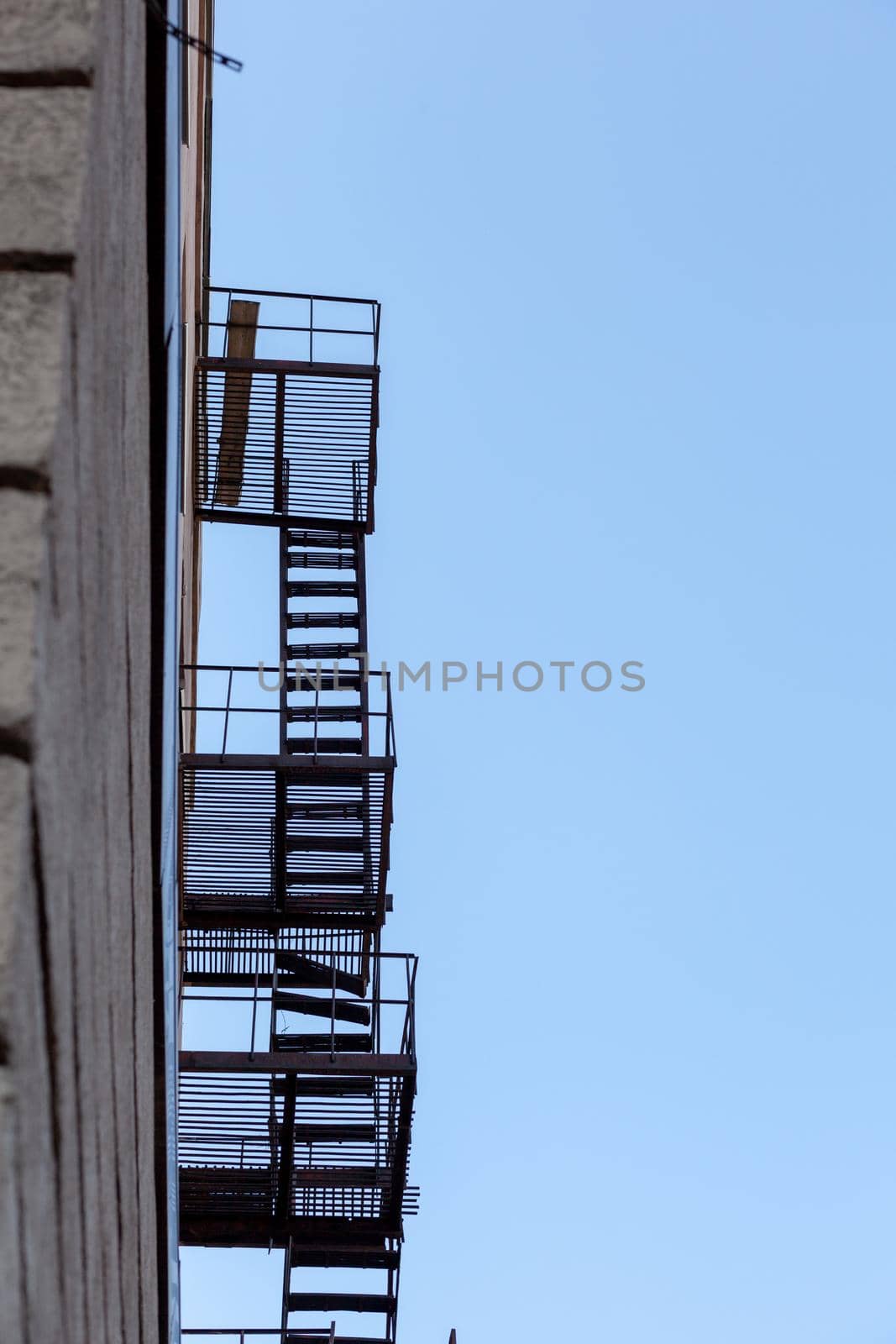 Silhouette of a fire escape on a high-rise building against a blue sky by AnatoliiFoto