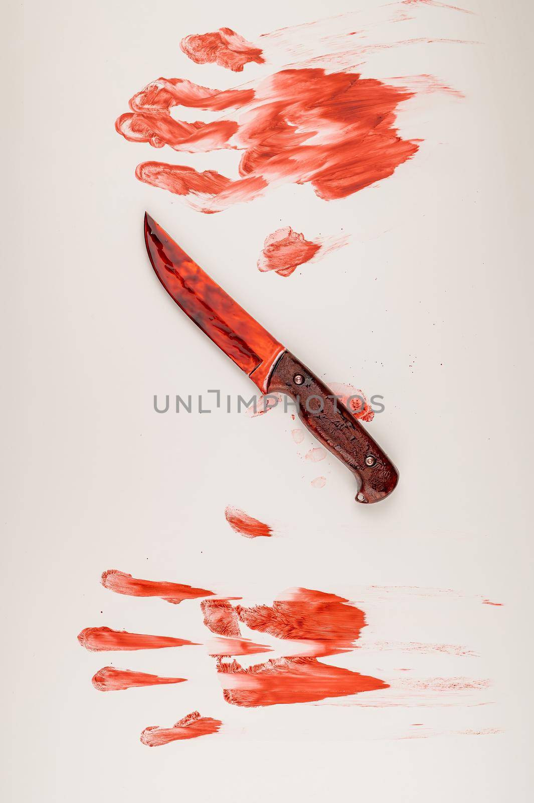 Bloody knife and hand prints in blood on a white table