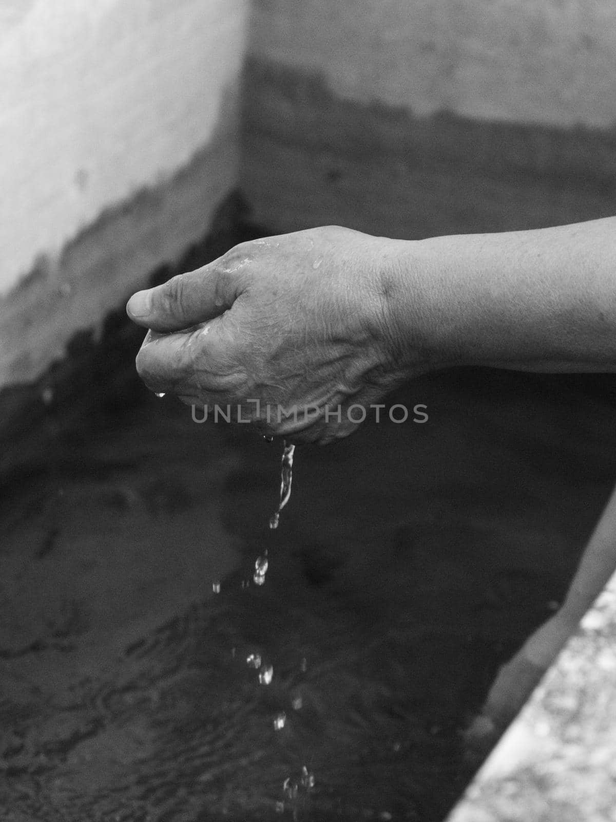 Woman watering and washing on a public foutain in Castell'Arquato Italy.Pure and precious to nature. Shot of hands held out to catch a stream of water outside.