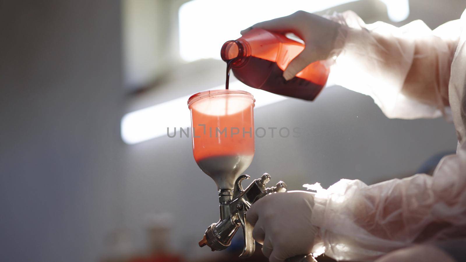 Red paint for car painting. Spray gun for car painting. Industrial spray painting process. Paint-spraying gun is getting used by the worker to colour the car. Car painting with professional spray gun