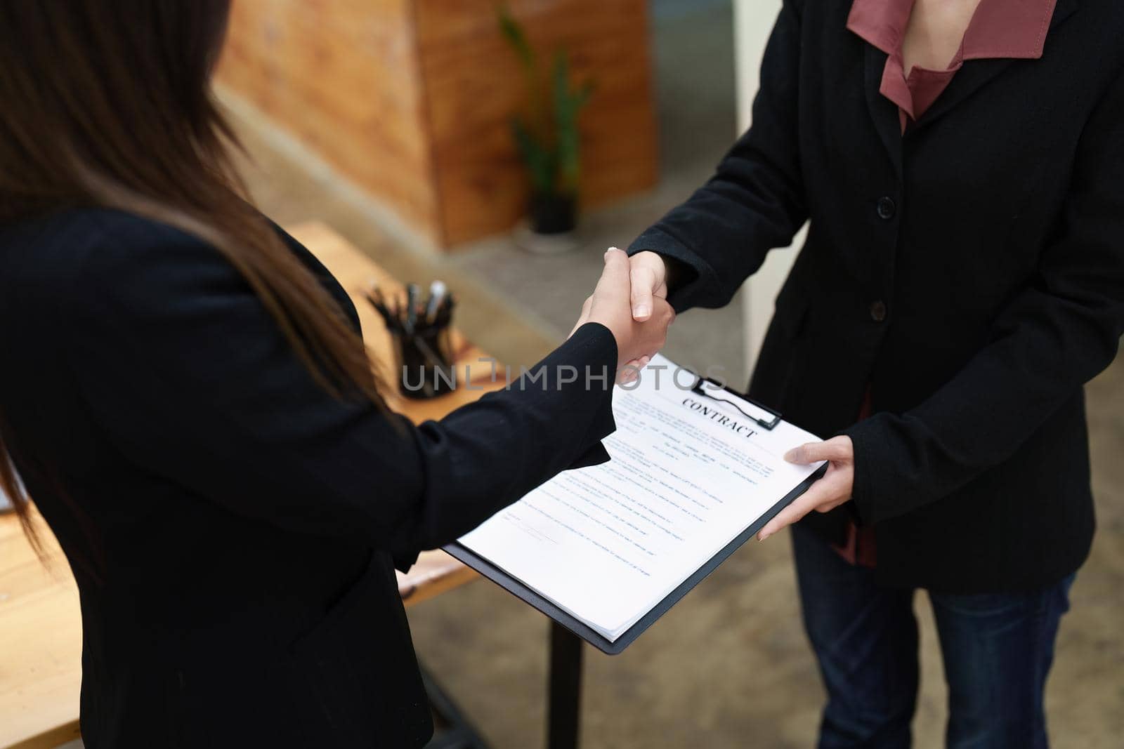 business merger, Asian businesswoman shake hands at the conference room with showcase their collaboration to strengthen their marketing efforts. by Manastrong