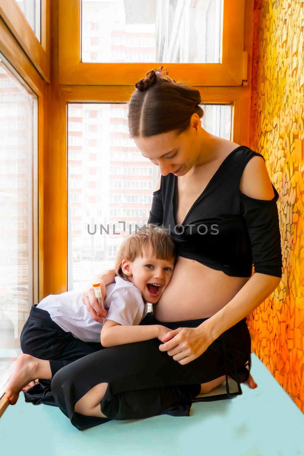 Cute little boy showing love towards unborn baby in mother's tummy at home by kajasja