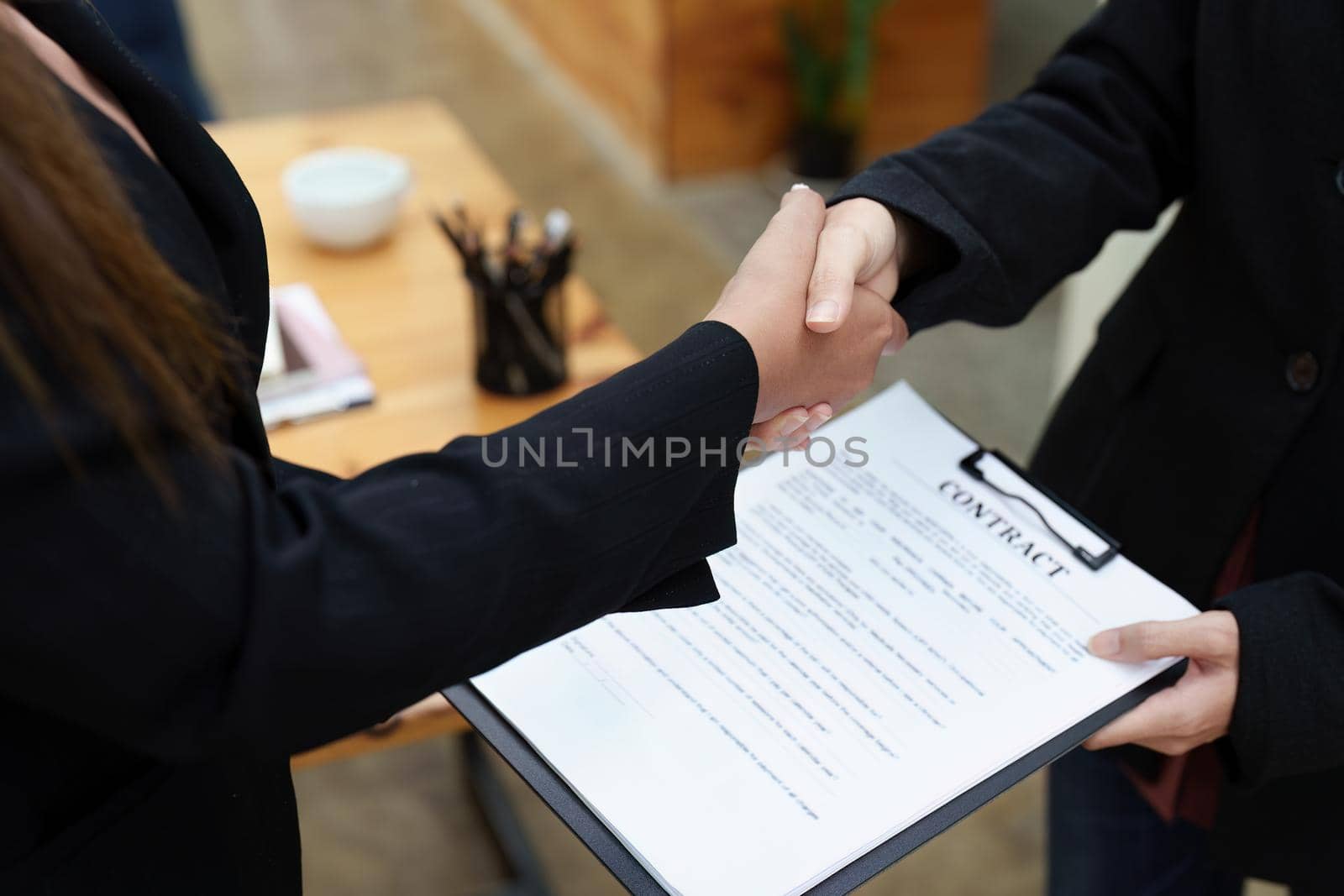 business merger, Asian businesswoman shake hands at the conference room with showcase their collaboration to strengthen their marketing efforts. by Manastrong