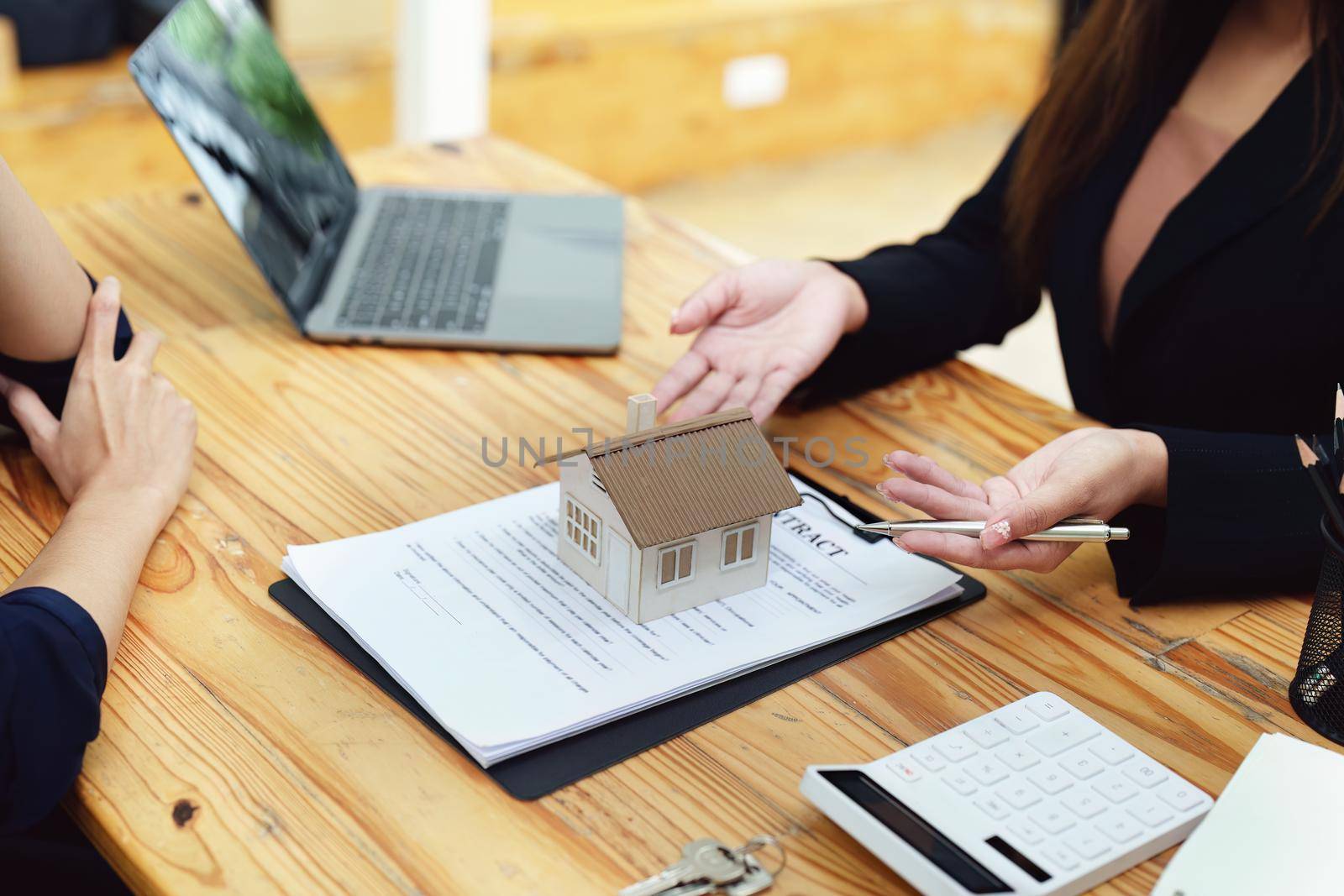 Asian female bank employee asking a customer to read the contract before signing to agree to buy a house, real estate concepts by Manastrong