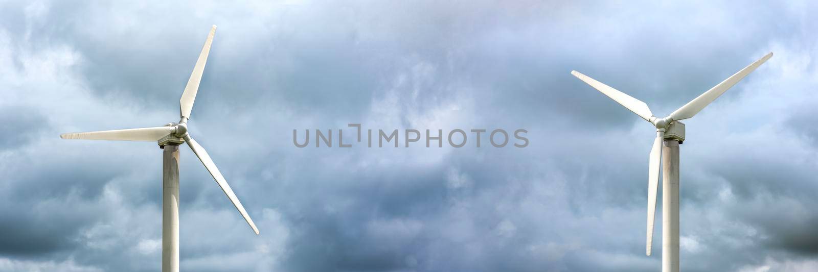 Windmills for electricity generation. Wind turbine against the background of a dark gloomy sky, windy weather, place to insert text