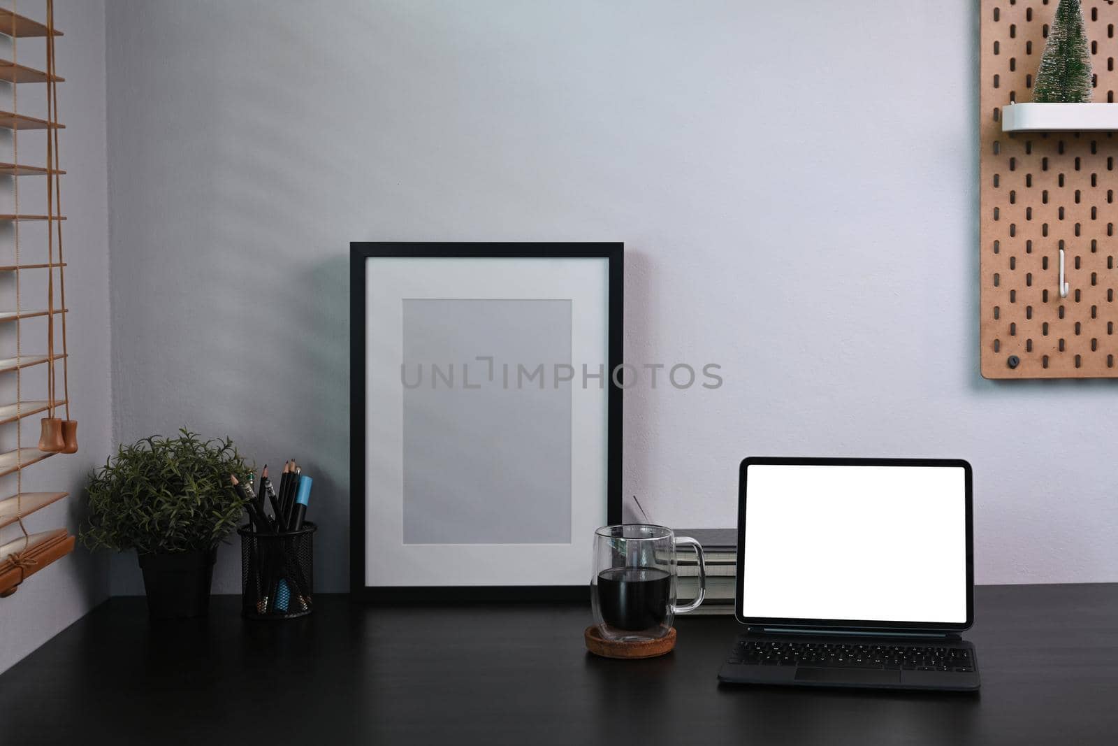 Front view computer laptop with blank display, picture frame and houseplant on black table.