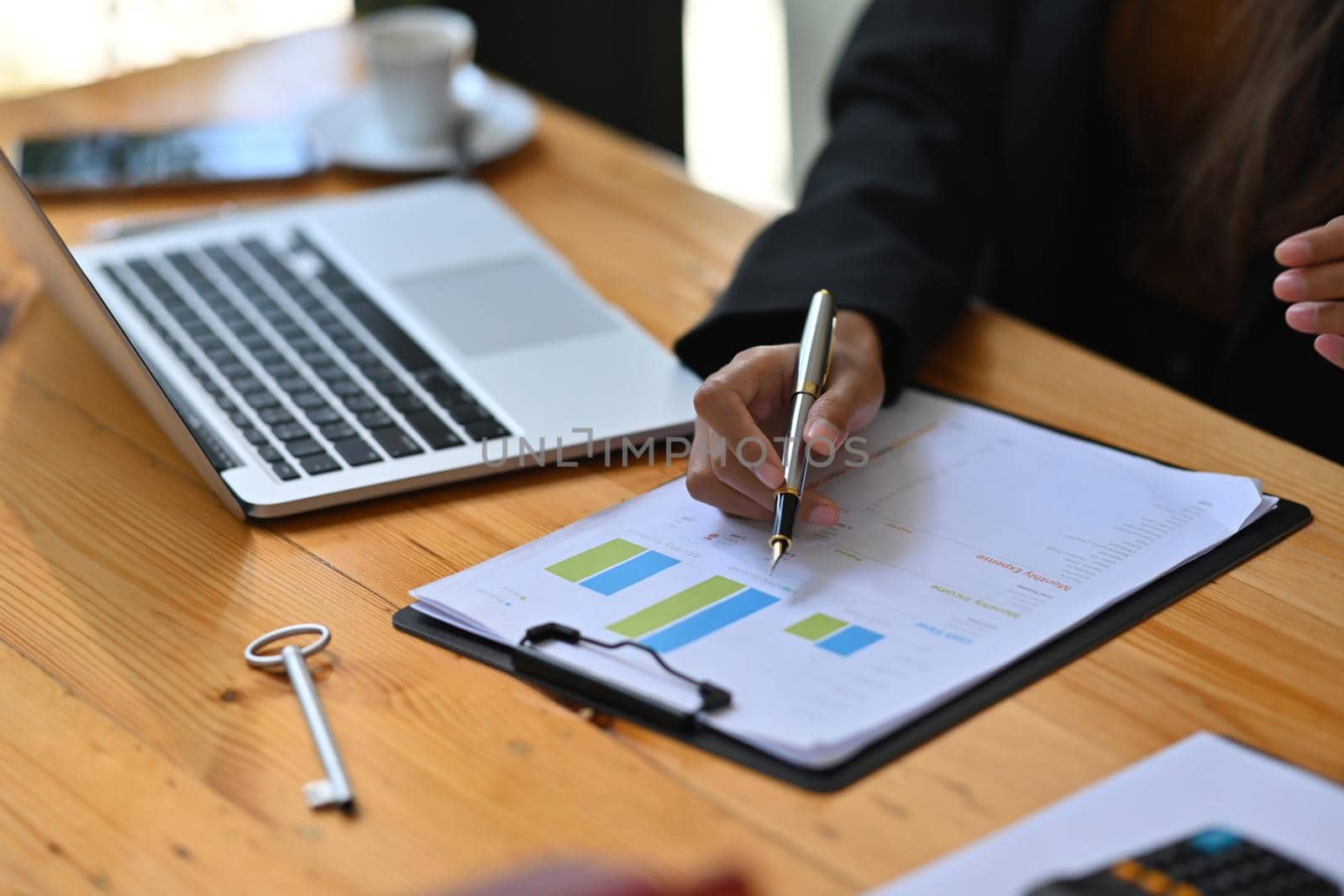 Businesswoman working with laptop and writing information on financial document.