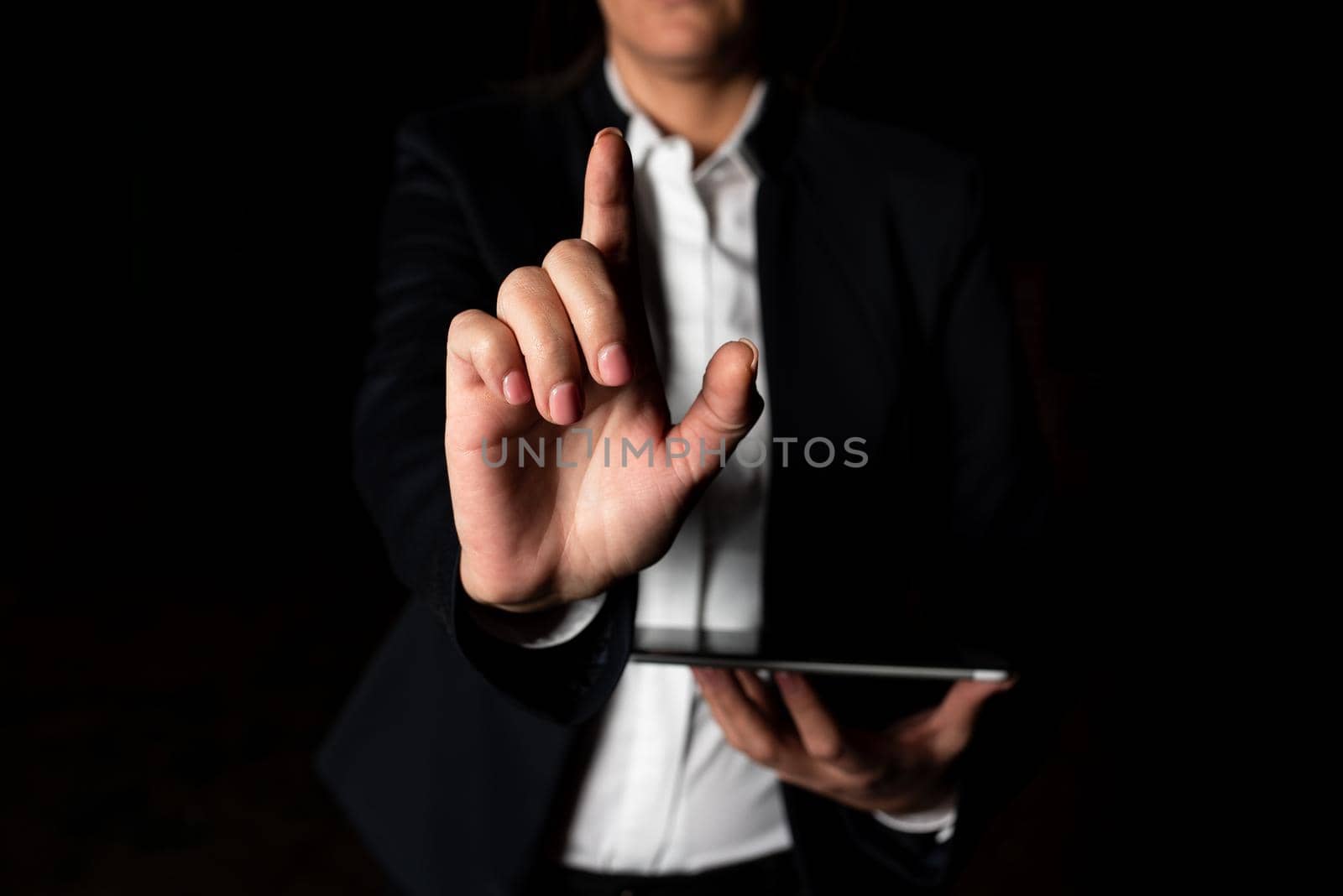 Businesswoman Holding Tablet And Pointing With One Finger On Important Message. Executive In Suit Presenting Crutial Information. Woman Showing Critical Announcement. by nialowwa