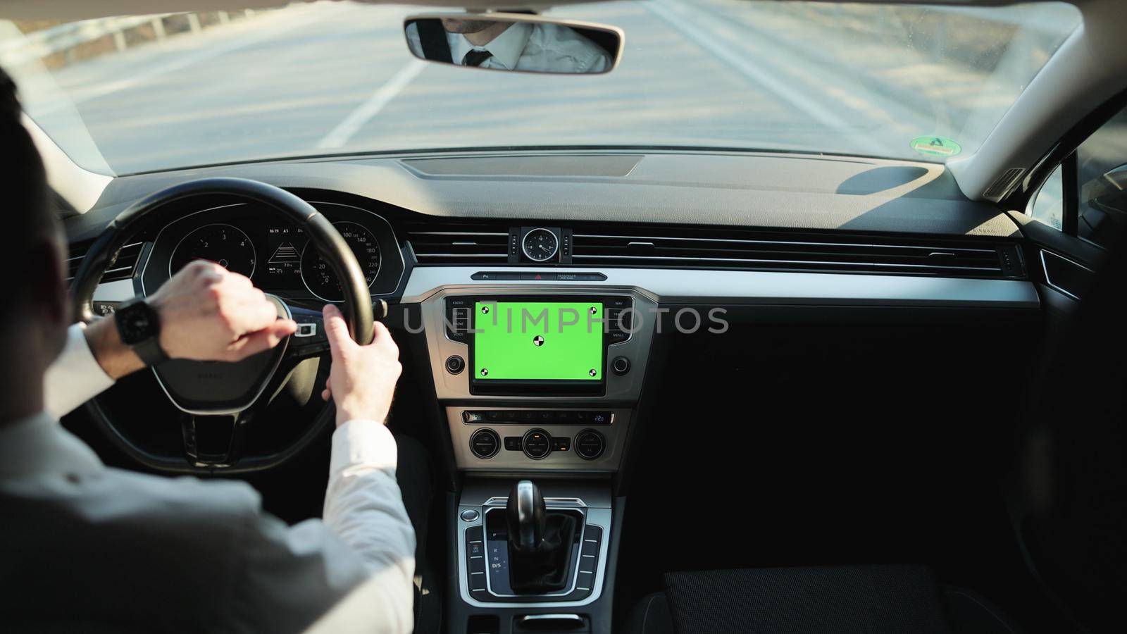 Back view of classic casual businessman in white shirt using smart watch on his hands while driving a car with greenscreen mock-up display dashboard service menu application. Navigation. Map. Driver