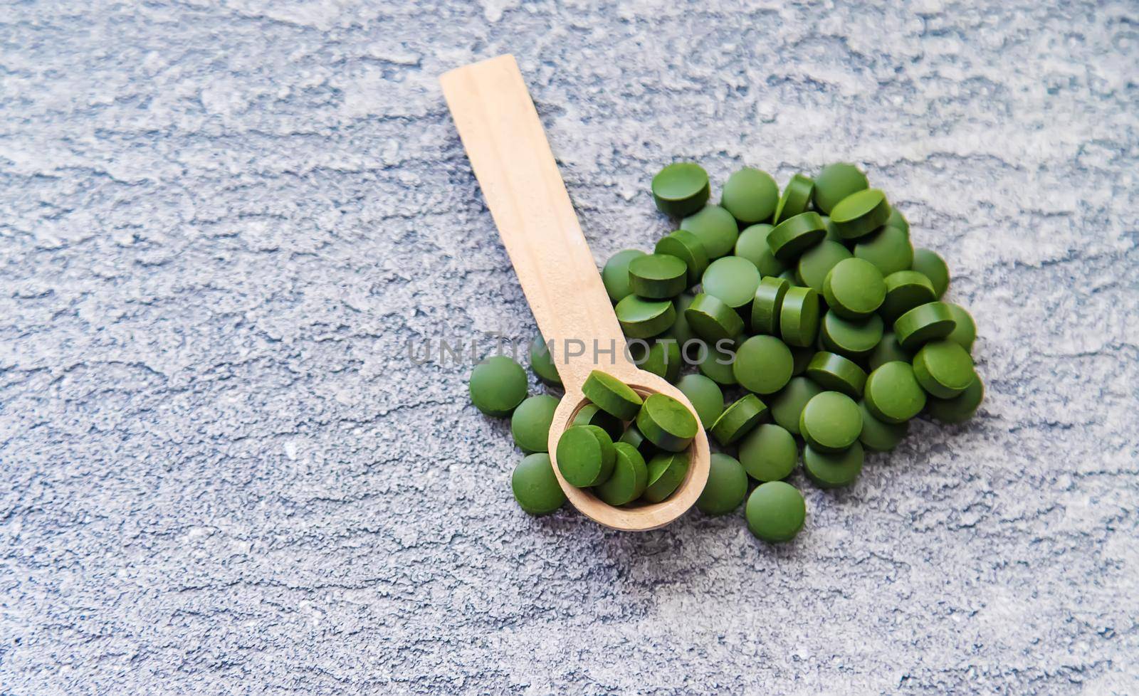 Green pills of chlorella and spirulina. Selective focus drink