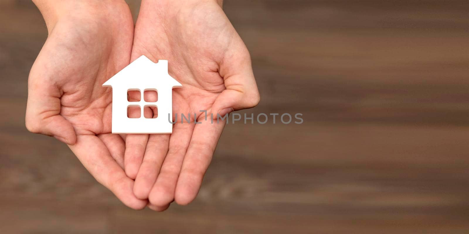 Hands are holding a toy house. Real estate purchase, homeless housing and real estate, family home insurance concept. space for text.