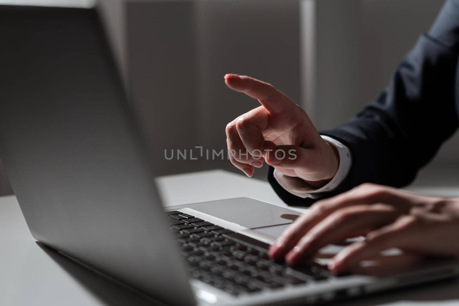 Businesswoman Typing Recent Updates On Lap Top Keyboard On Desk With Cellphone And Pointing Important Ideas One Finger. Woman In Office Writing Late Messages On Computer. by nialowwa