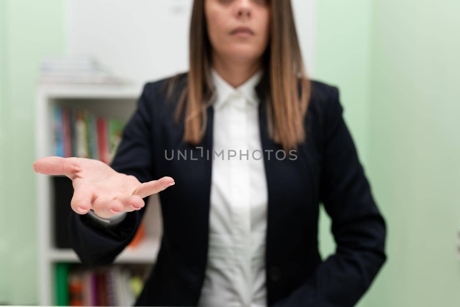 Businesswoman Holding Important Message In One Hand. Woman In Suit Showing New Crutial Idea In A Palm. Executive Presenting Updated Critical Information. by nialowwa