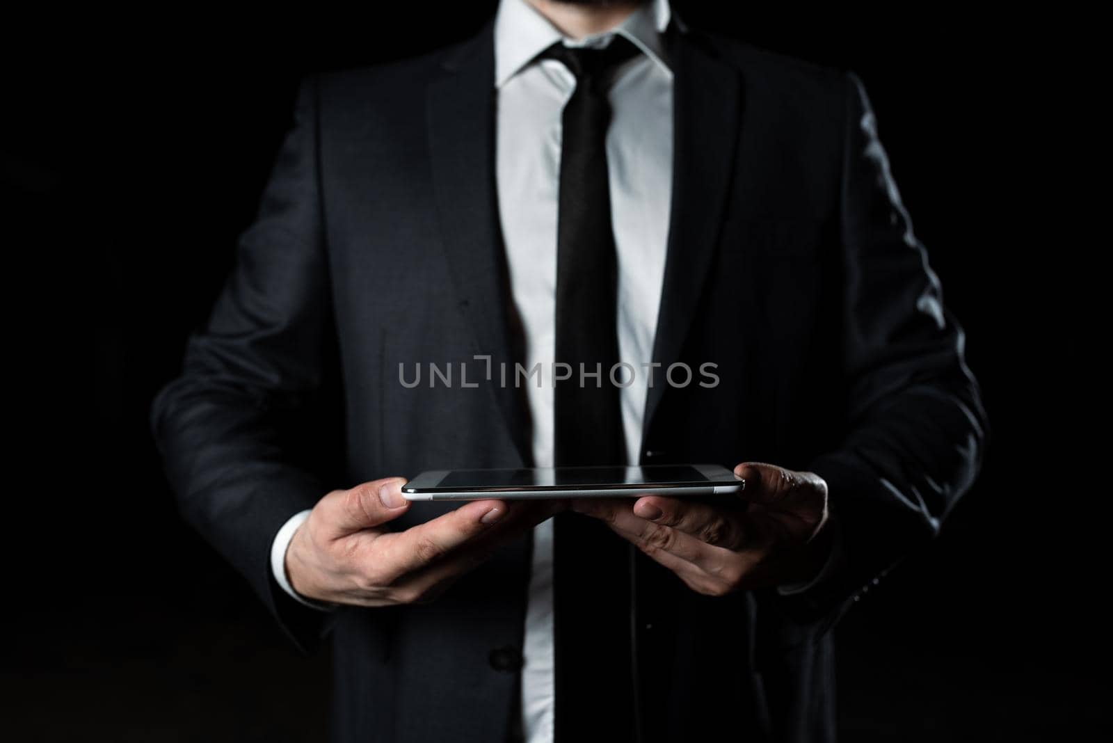 Businessman Holding Tablet With Both Hands And Presenting Important Data. Man In Suit Showing Crutial Information. Executive Displaying Crutial Announcement. by nialowwa