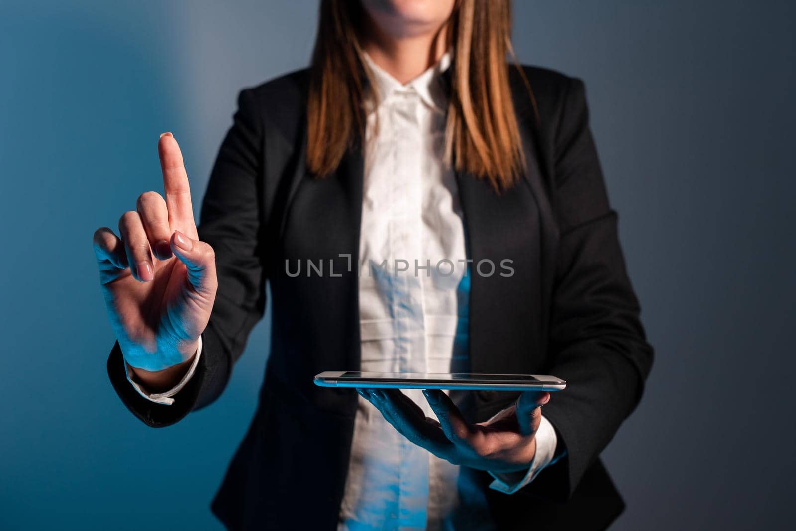 Businesswoman Holding Phone And Pointing With One Finger On Important Message On Desk With Lap Top. Executive In Suit Presenting Crutial Informations. by nialowwa