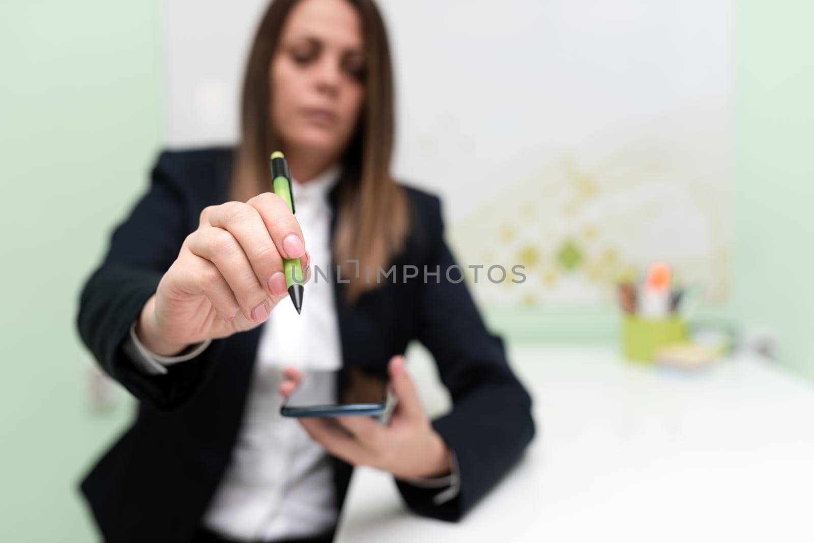 Businesswoman Holding Tablet And Pointing Important Informations With Pen In Hand. Woman Showing Recent Updates. Executive Displaying Late Achievements. by nialowwa