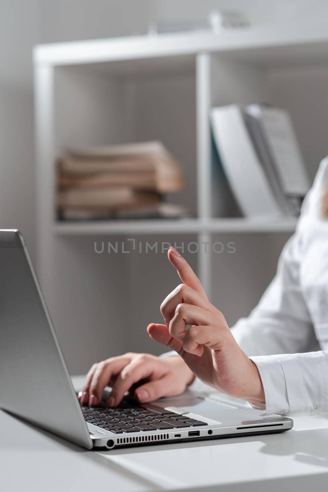 Businesswoman Typing Recent Updates On Lap Top Keyboard On Desk And Pointing Important Ideas With One Finger. Woman In Office Writing Late Messages On Computer. by nialowwa