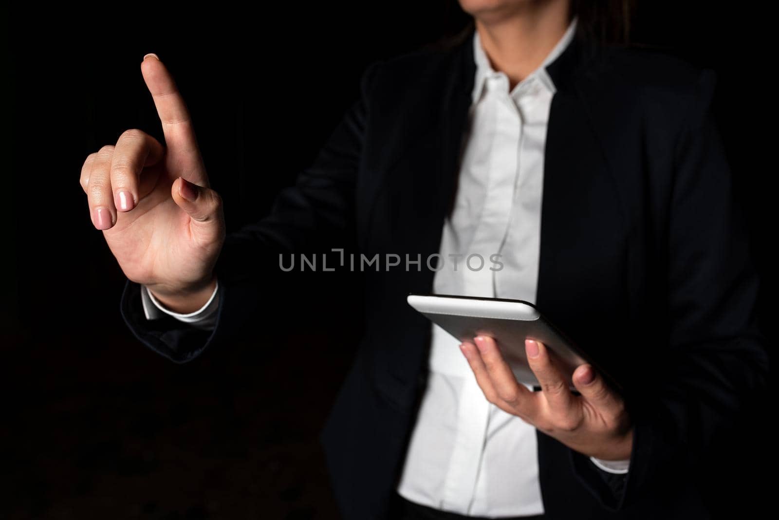 Businesswoman Holding Tablet And Pointing With One Finger On Important Message. Executive In Suit Presenting Crutial Information. Woman Showing Critical Announcement. by nialowwa