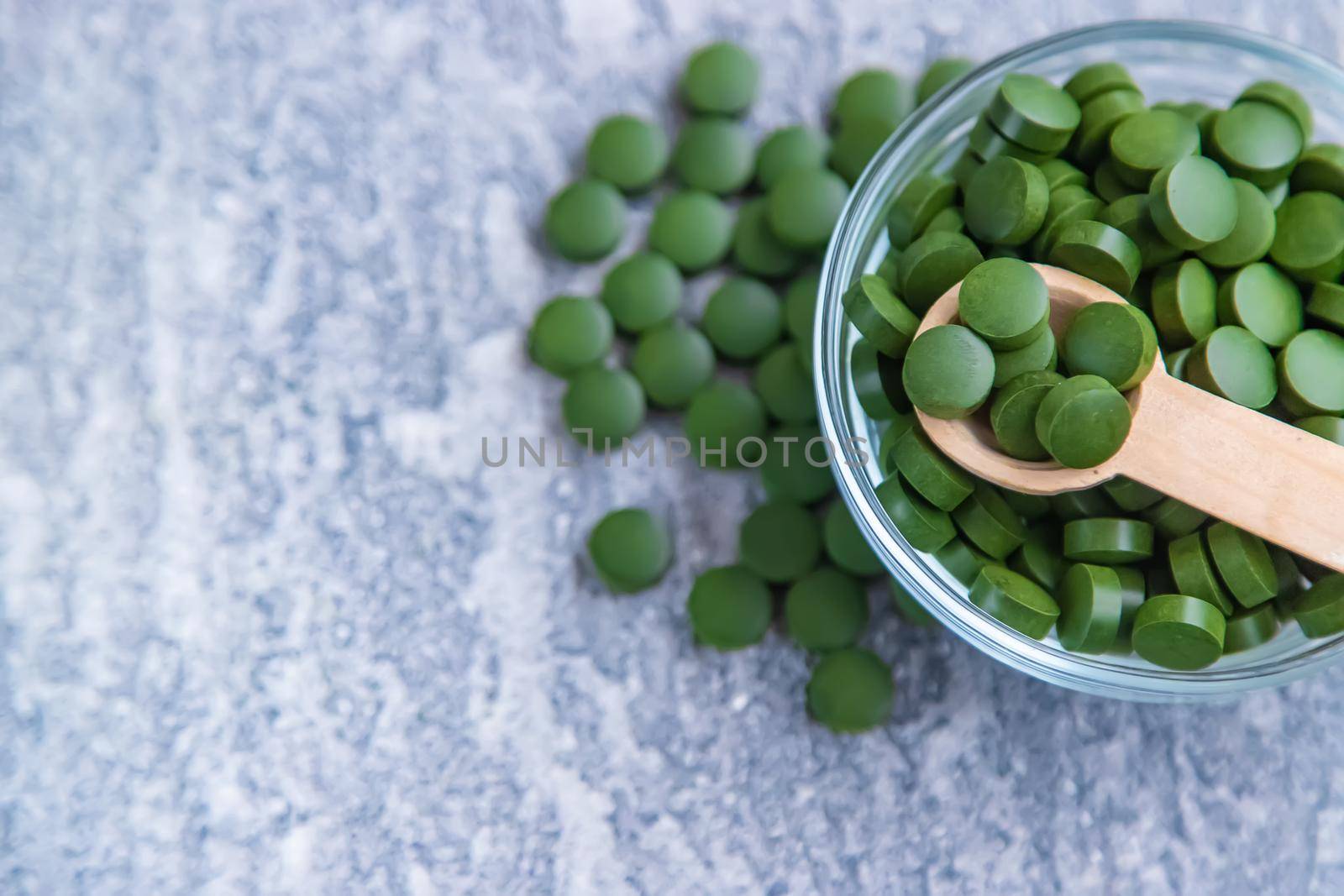 Green pills of chlorella and spirulina. Selective focus drink