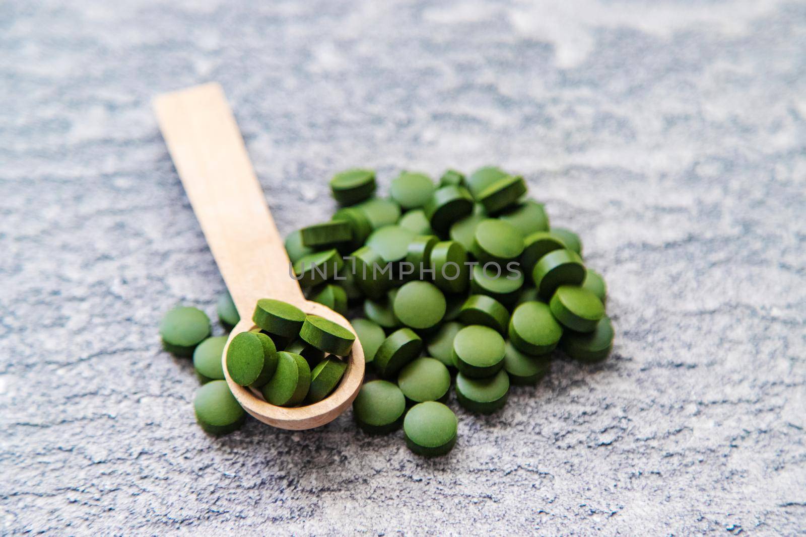 Green pills of chlorella and spirulina. Selective focus drink