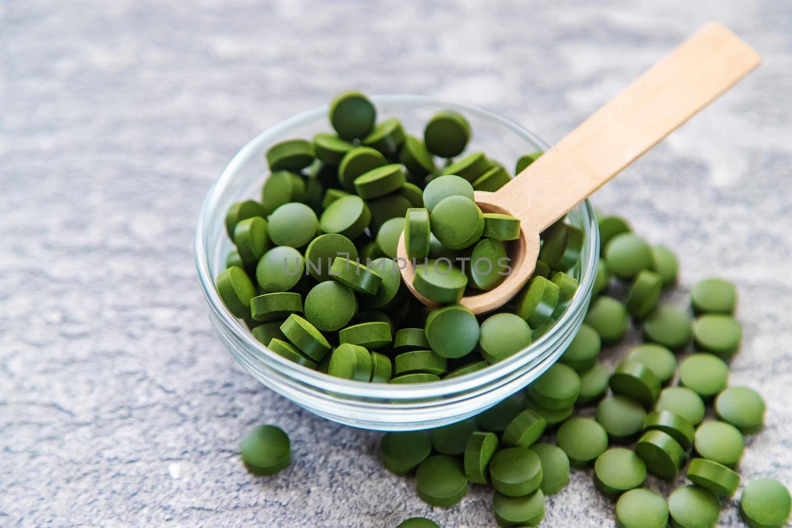 Green pills of chlorella and spirulina. Selective focus drink