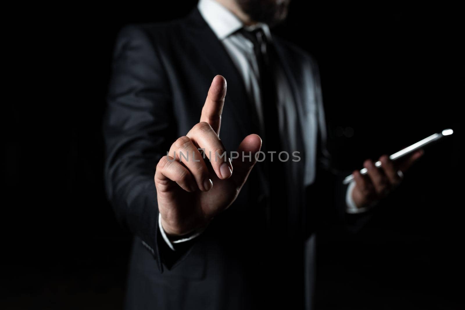 Businessman Holding Phone And Pointing With One Finger On Important Message. Executive In Suit Presenting Crutial Information. Gentleman Showing Critical Announcement. by nialowwa